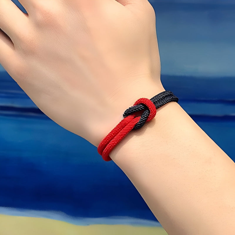 Bracelet cordon rouge et bleu marine avec noeud simple ajusté au poignet.