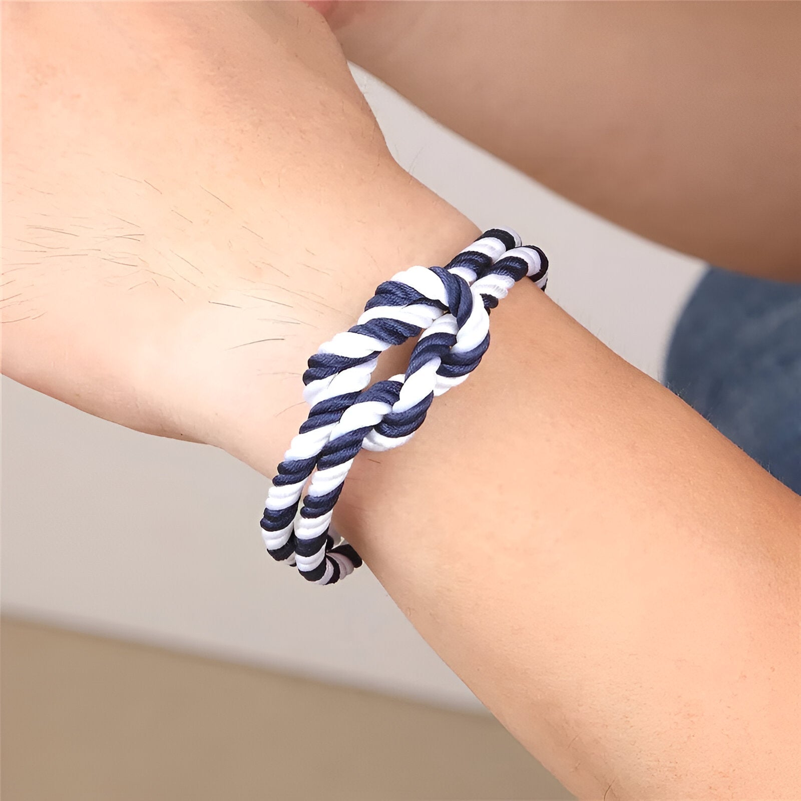 Bracelet cordon épais bleu et blanc tressé avec noeud sur poignet peau claire.