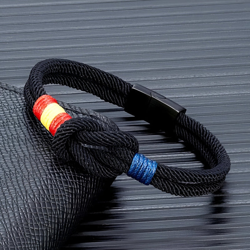 Bracelet cordon noir avec nœud et drapeau espagnol en tissu rouge, jaune et bleu.