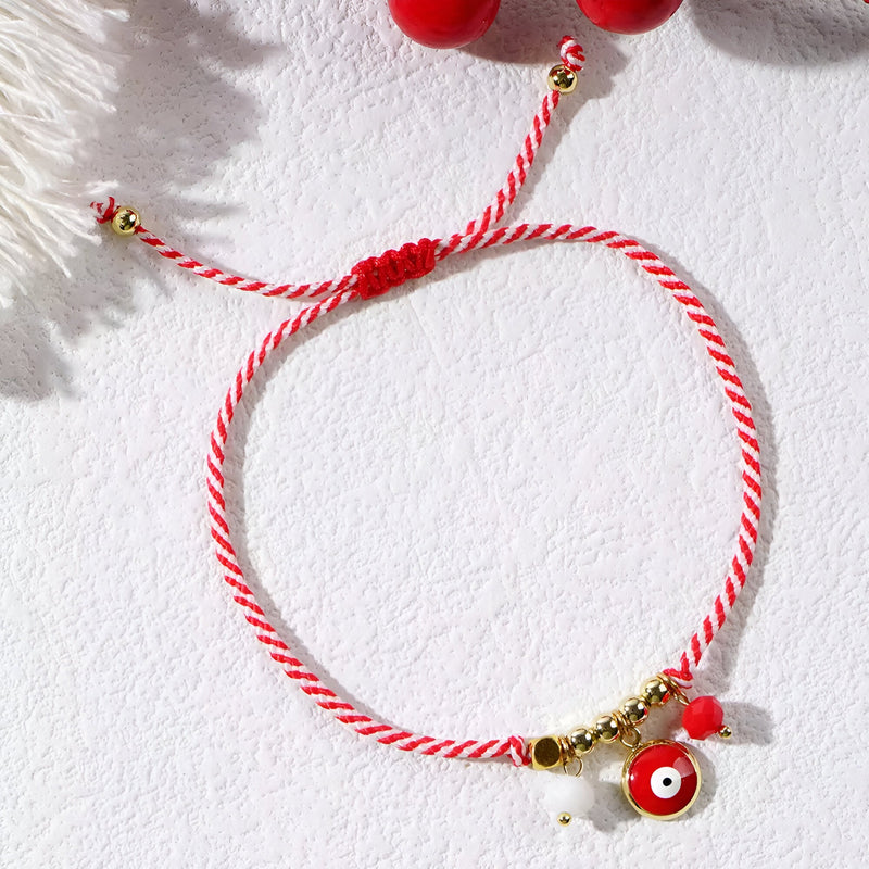 Bracelet cordon rouge tressé avec pendentifs or et œil de dzi rouge pour femme.