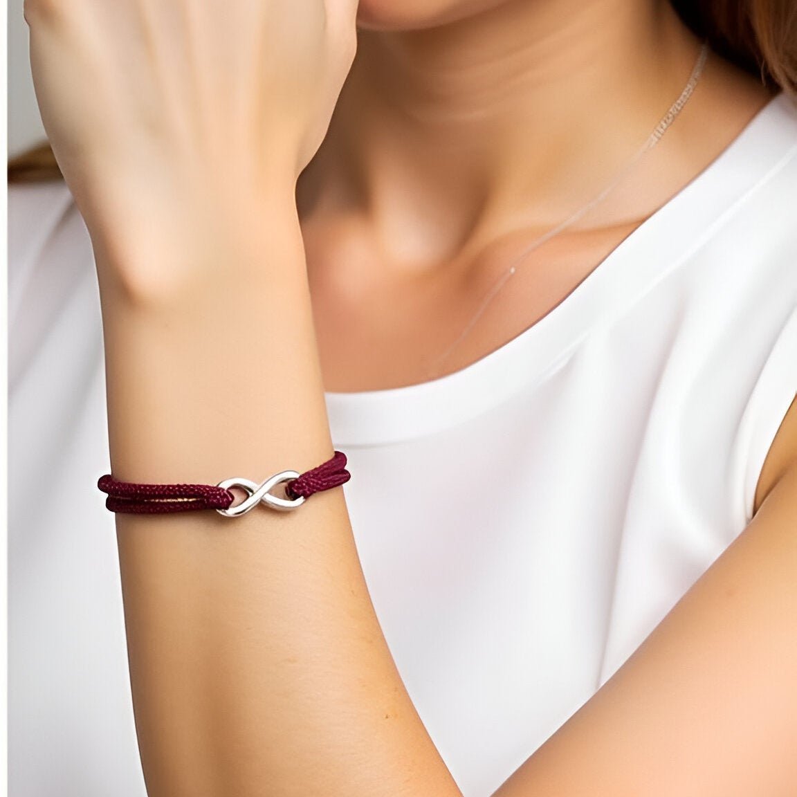 Bracelet cordon bordeaux avec ornement infini en métal argenté, ajustable sur poignet féminin.