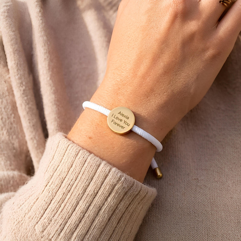 Bracelet cordon blanc avec médaillon rond en acier inoxydable gravé, style minimaliste et élégant.