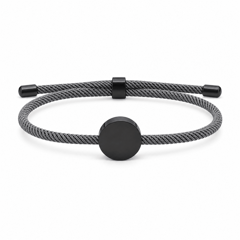 Bracelet Dax Noir / Gris, cordon ajustable et médaillon rond, posé de face sur fond blanc