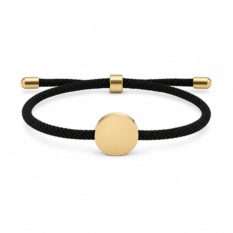 Bracelet Dax Or / Noir, cordon ajustable et médaillon rond, posé de face sur fond blanc