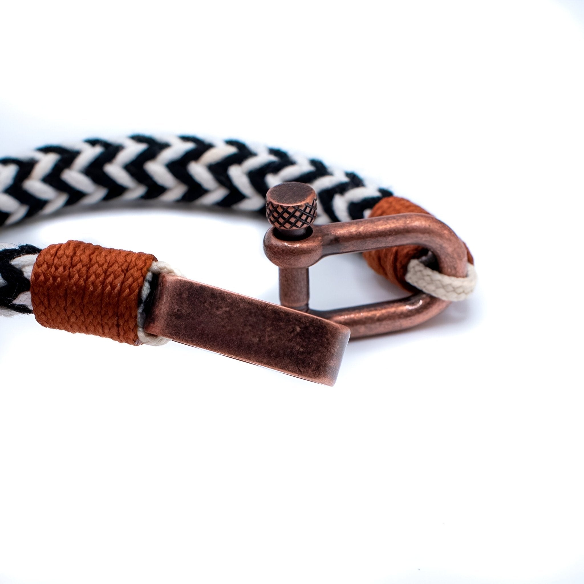 Bracelet cordon noir et blanc tressé avec mousqueton ancien en métal cuivreux et détail cuir marron.