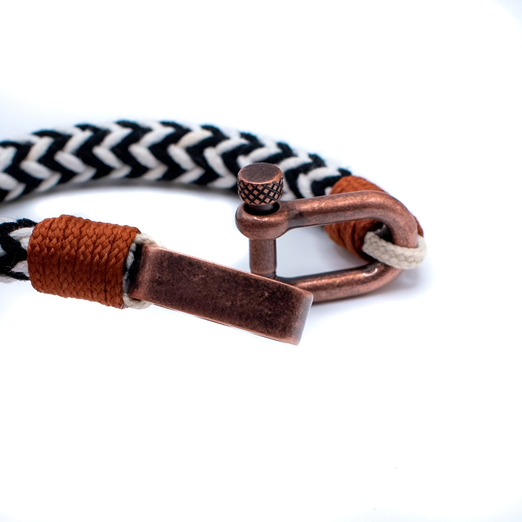 Bracelet cordon noir et blanc tressé avec mousqueton ancien en métal cuivreux et détail cuir marron.