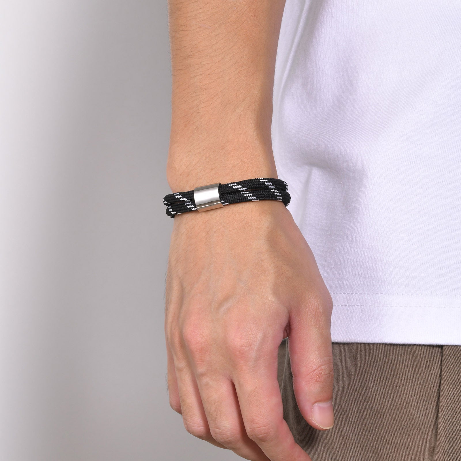 Bracelet cordon homme noir rayé blanc avec fermoir métallique argenté.