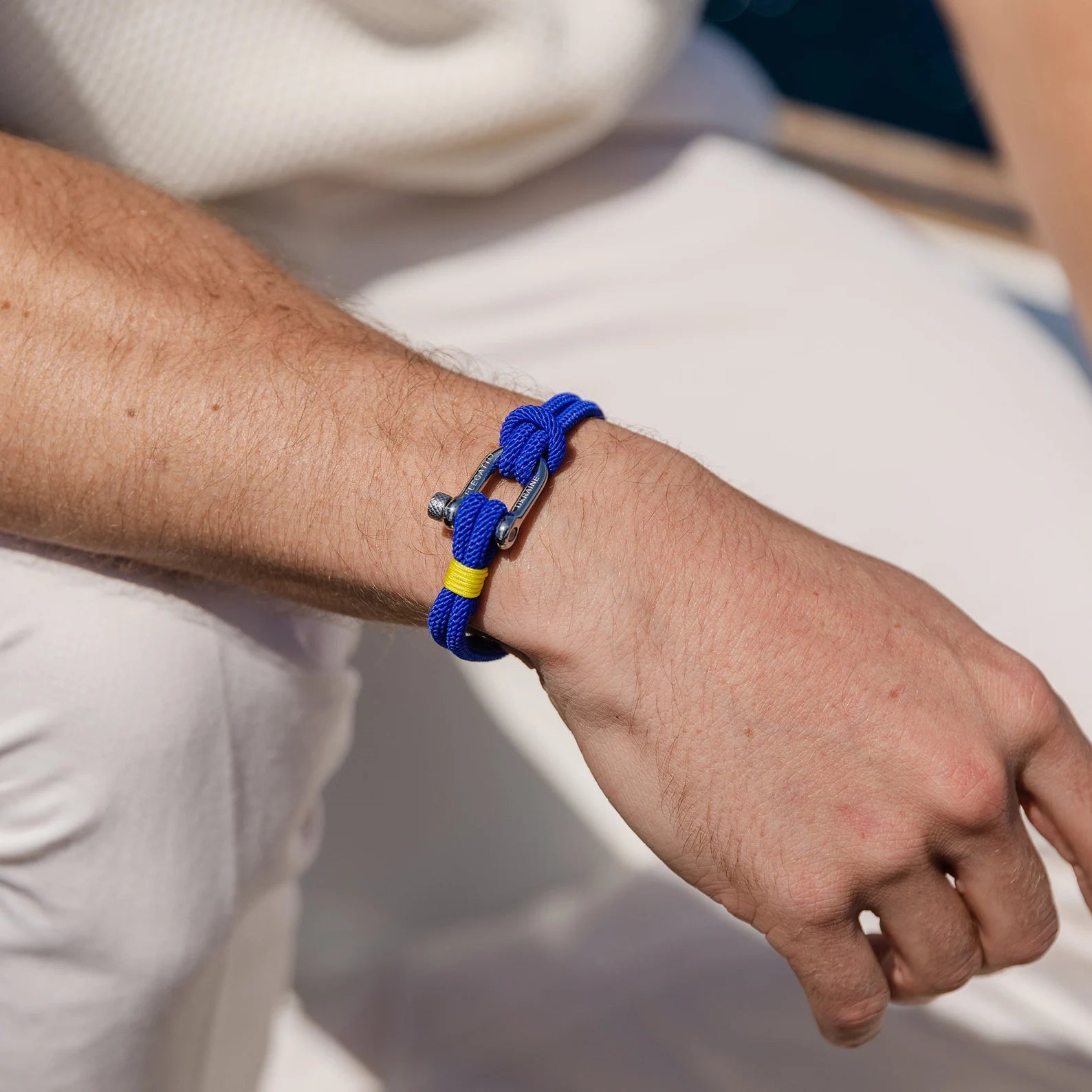 Bracelet cordon bleu pour homme avec mousqueton argenté et détail jaune, style sportif.