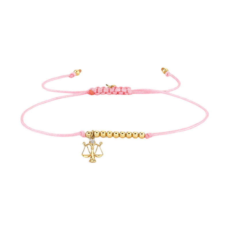 Bracelet cordon rose avec perles dorées et pendentif Balance astrologique en métal doré.
