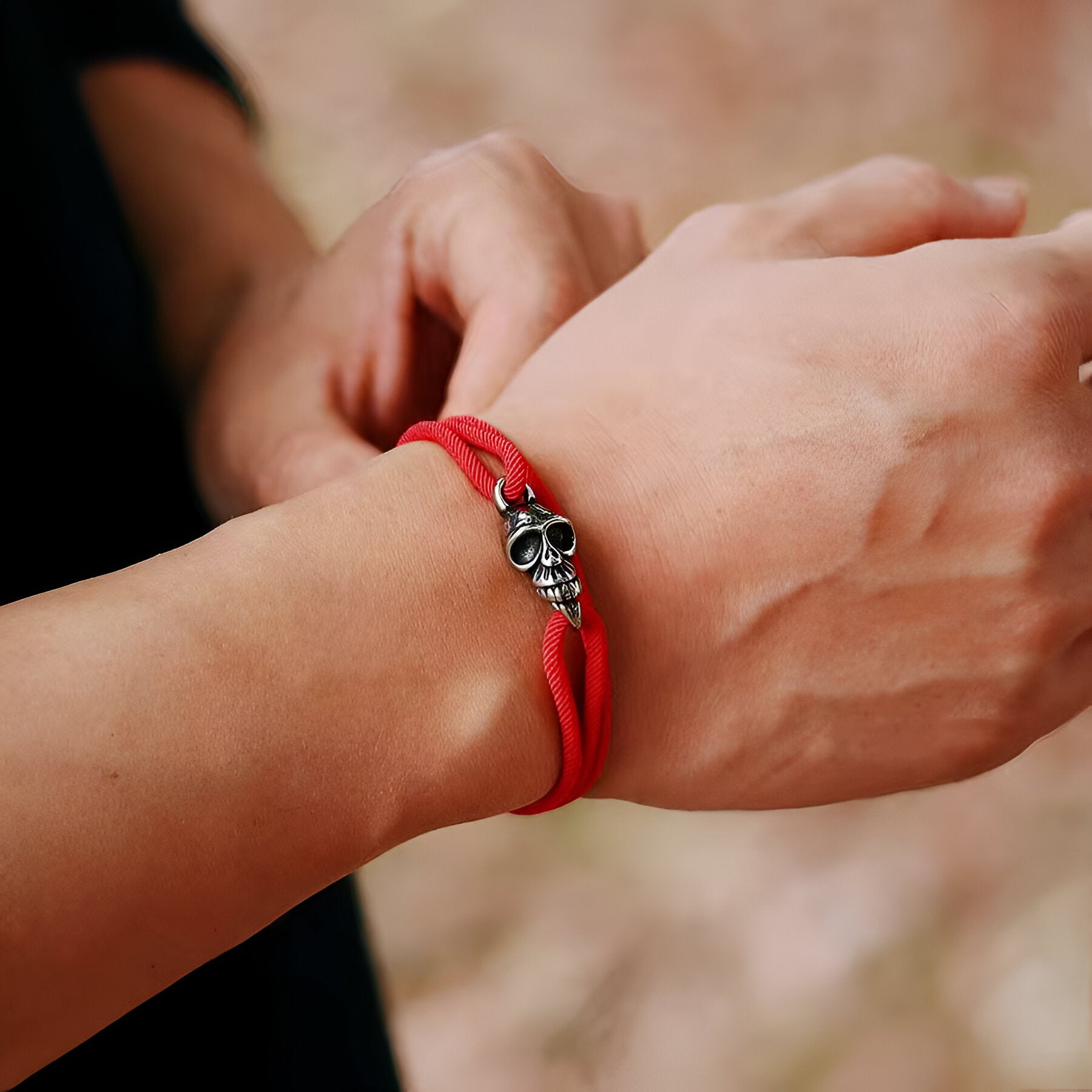Bracelet cordon rouge pour homme avec tête de mort en métal au centre.