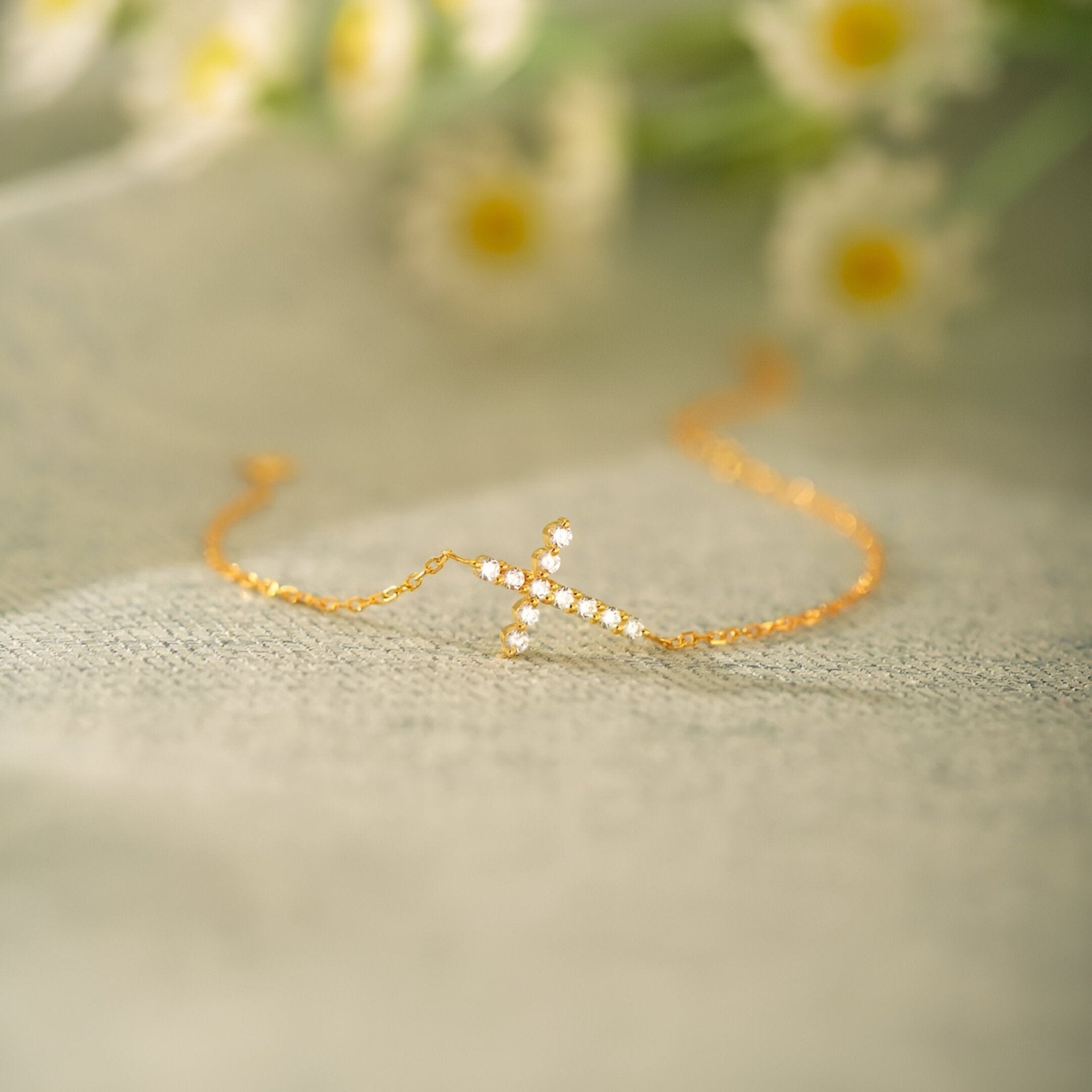 Bracelet fin en argent sterling avec croix chrétienne ornée de petites pierres scintillantes.