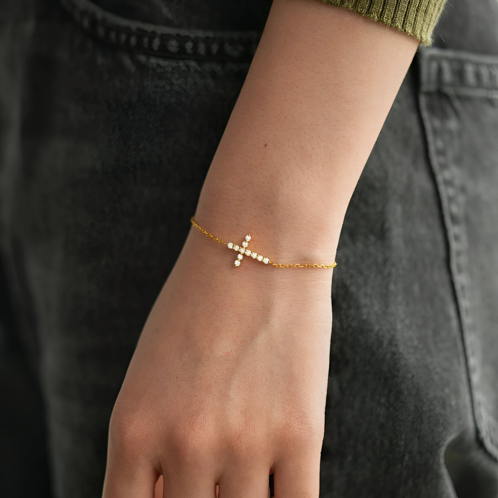 Bracelet fin en argent doré avec une petite croix scintillante pour femme.