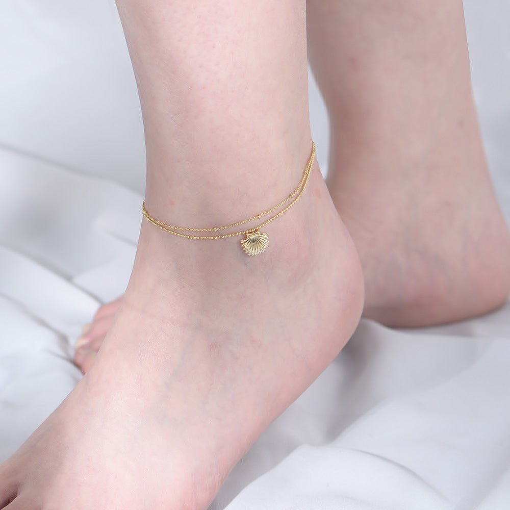 Bracelet de cheville en argent sterling avec pendentif coquillage doré fin et délicat sur la peau claire.