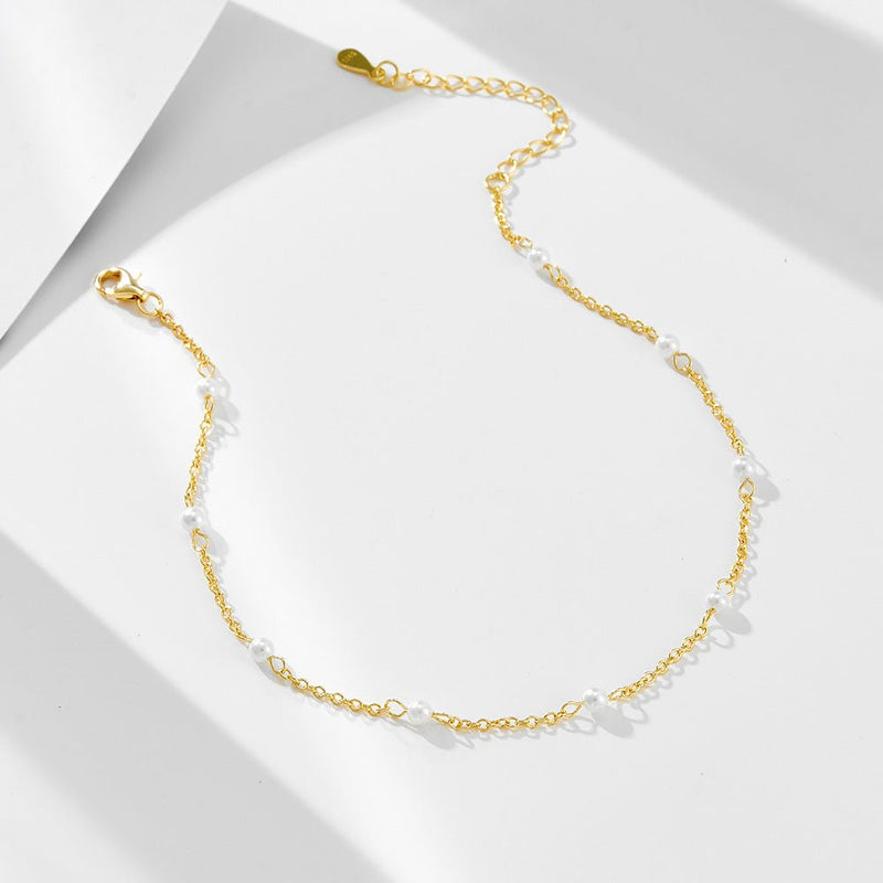 Bracelet de cheville en or avec petites perles d'eau douce blanches, chaîne fine et fermoir ajustable.