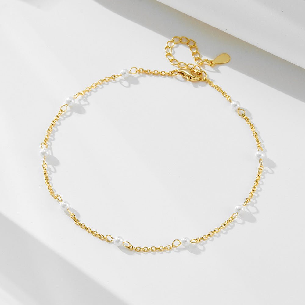 Bracelet de cheville en or avec petites perles d'eau douce espacées sur chaîne fine délicate.