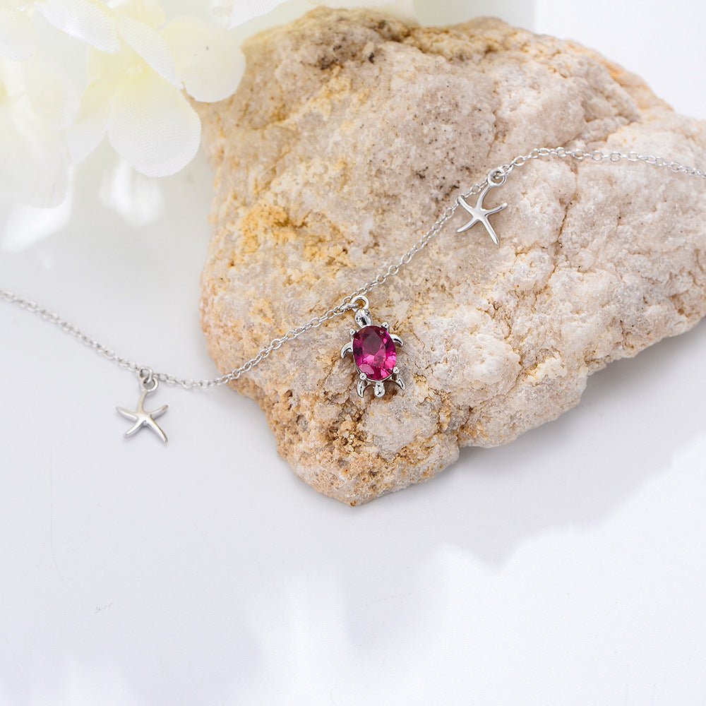 Bracelet de cheville en argent sterling avec pendentifs tortue, étoiles de mer et pierre rose sur chaîne fine.