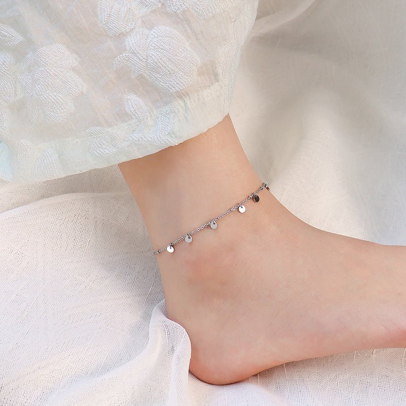 Bracelet de cheville en titane argenté avec multiples médaillons ronds délicats.