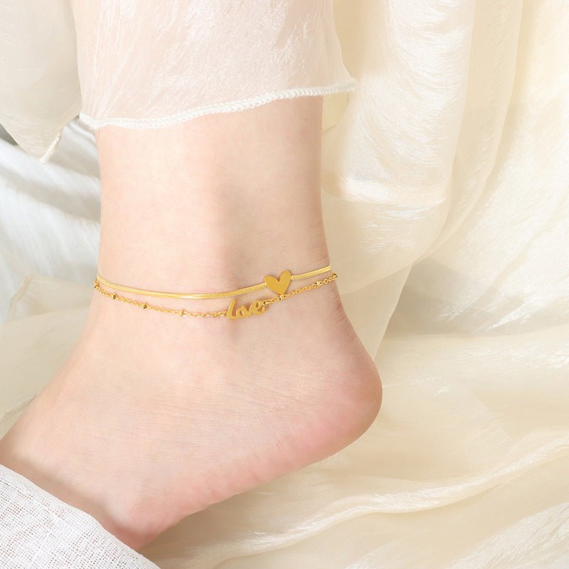 Bracelet de cheville en titane doré avec pendentifs cœur et inscription love pour femme.