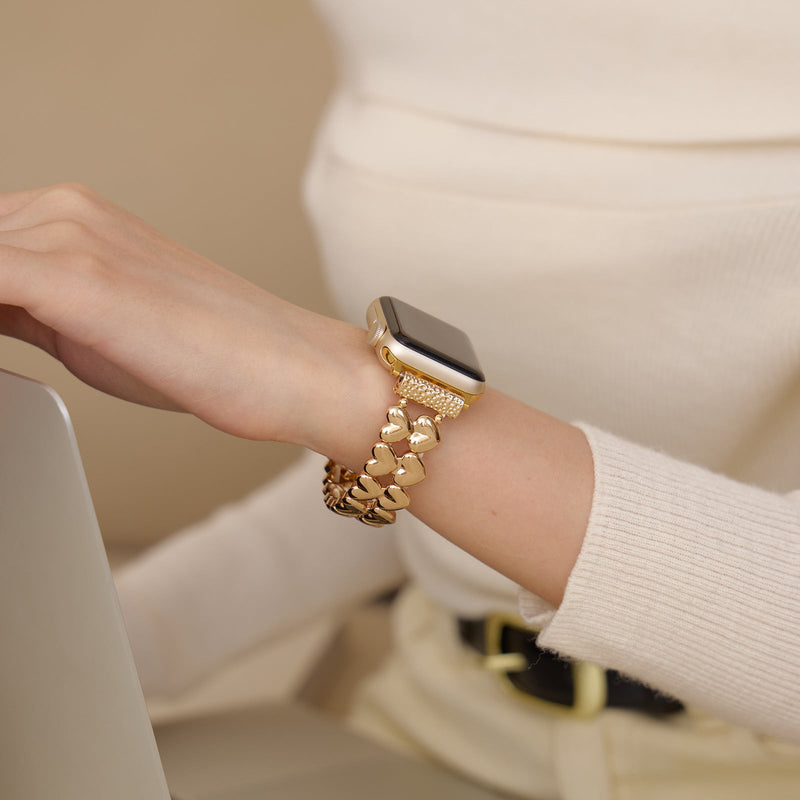 Bracelet Apple Watch doré à motifs cœurs, style élégant et féminin, porté au poignet.