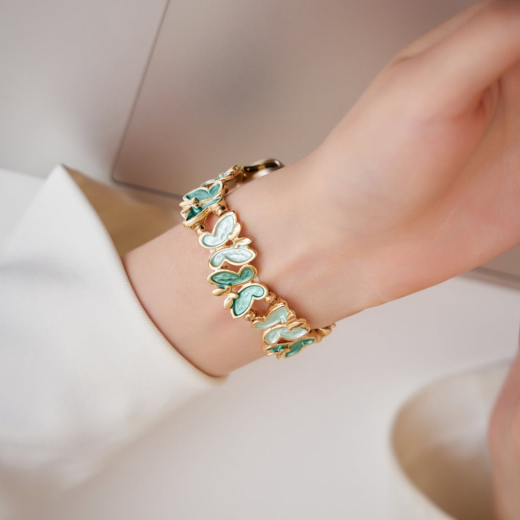 Bracelet Apple Watch Florencia en métal doré avec motifs papillons bleu et blanc élégants.