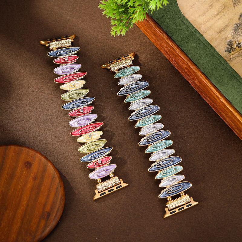 Deux bracelets pour Apple Watch multicolores avec motifs marbrés, boucles en or rose, posés sur fond marron.