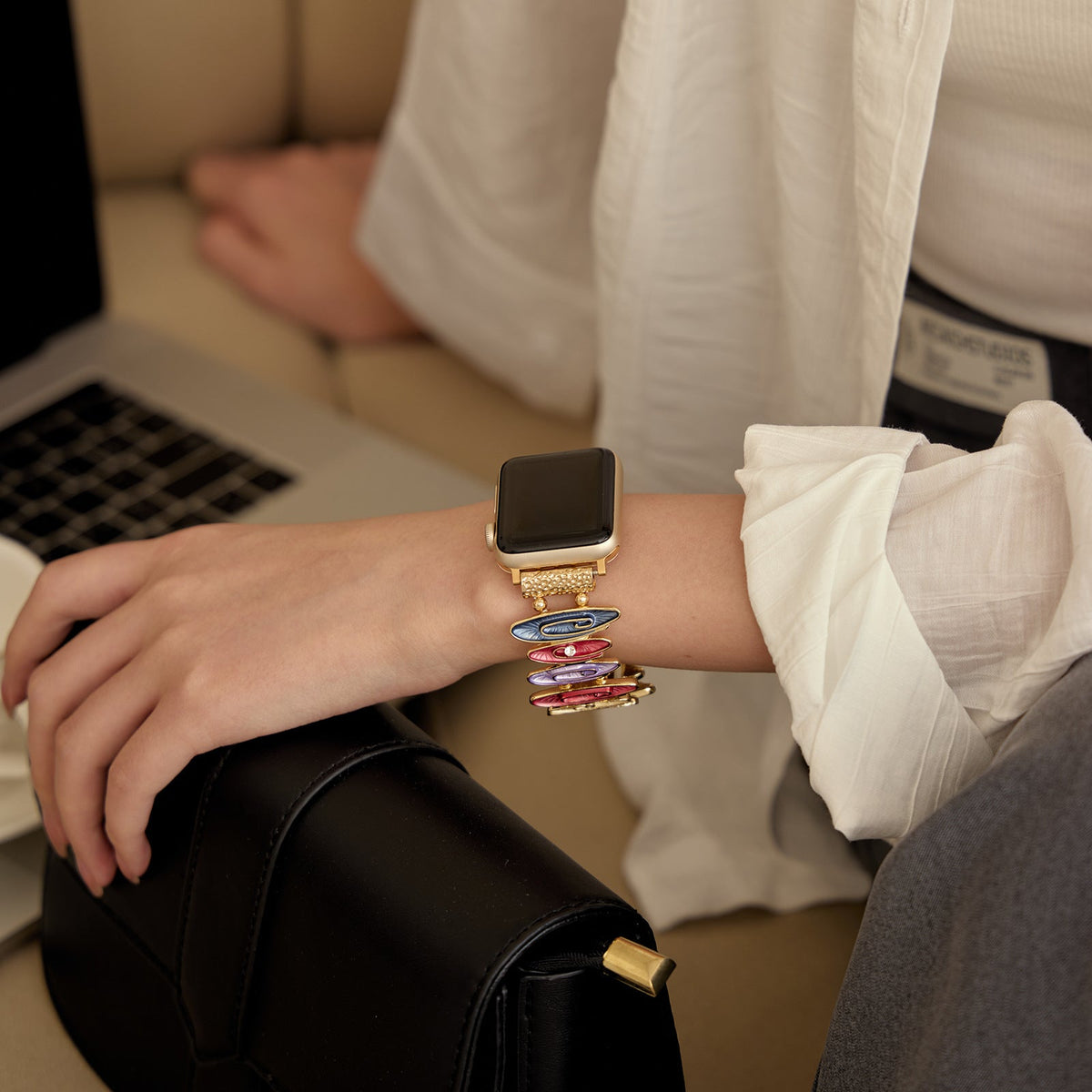 Bracelet coloré pour Apple Watch avec maillons minces et design élégant, porté au poignet féminin.
