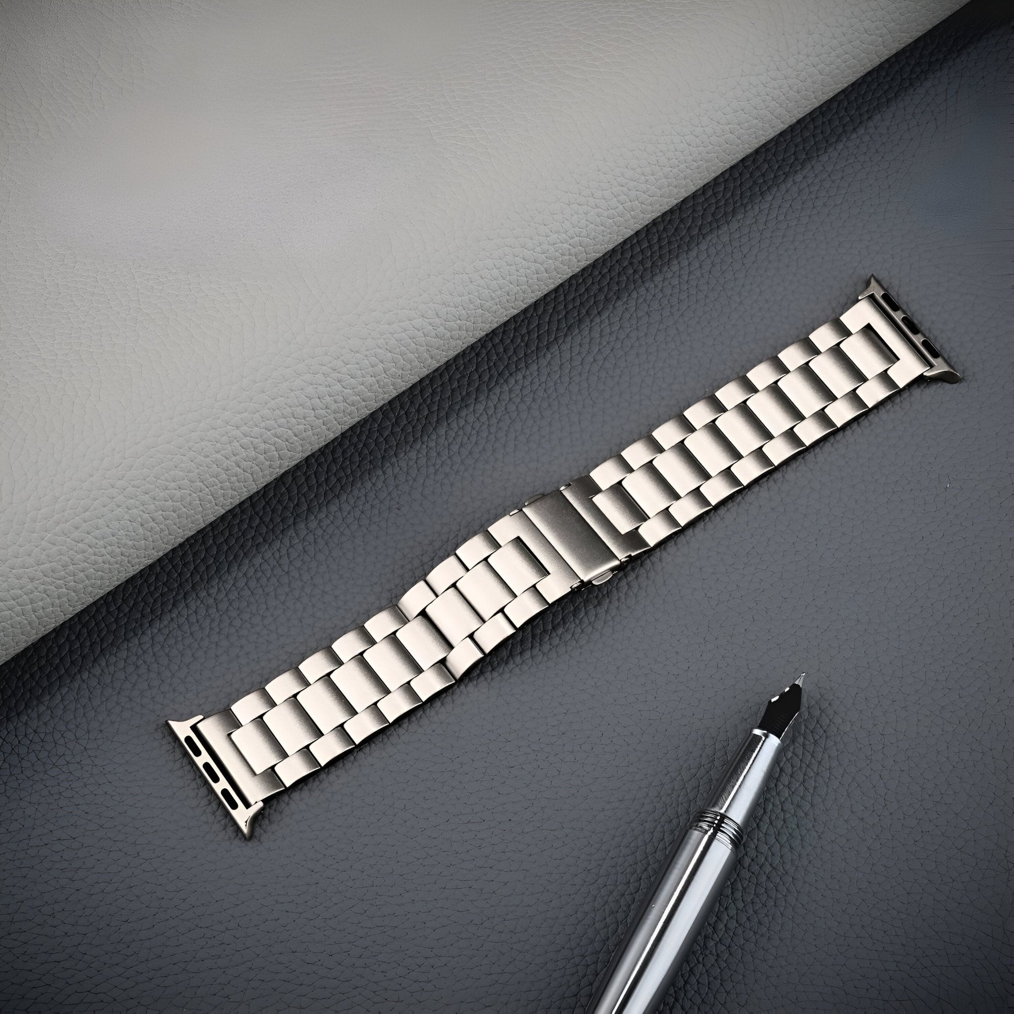 Bracelet Apple Watch en acier inoxydable argenté avec maillons larges et fermoir déployant.