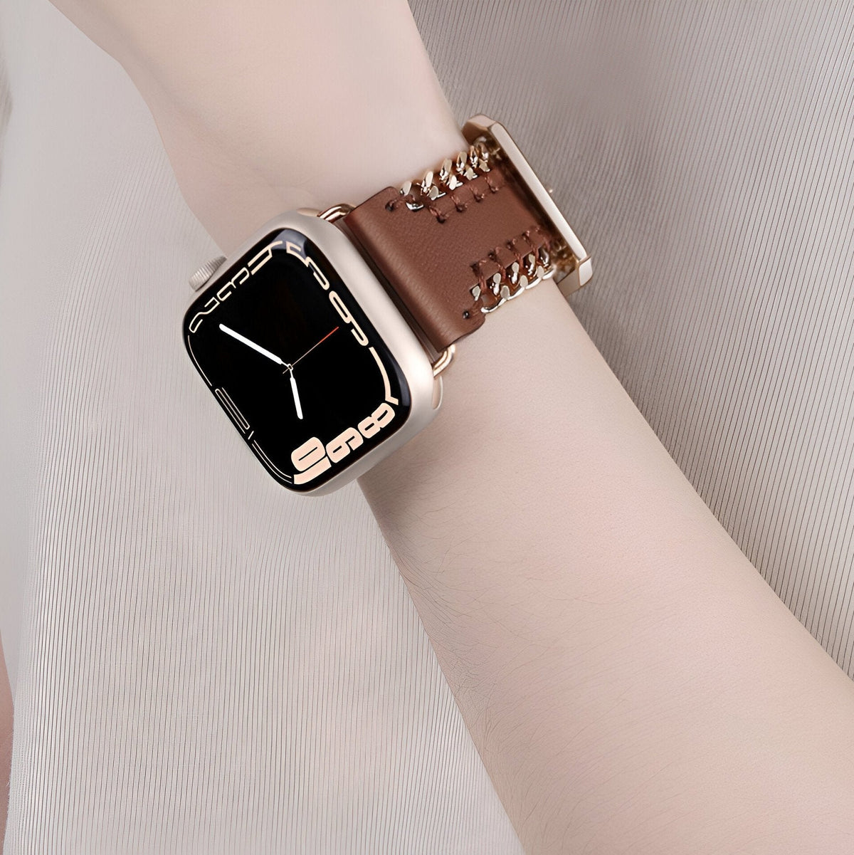 Bracelet Apple Watch cuir marron à chaîne dorée, couture apparente, boucle assortie.