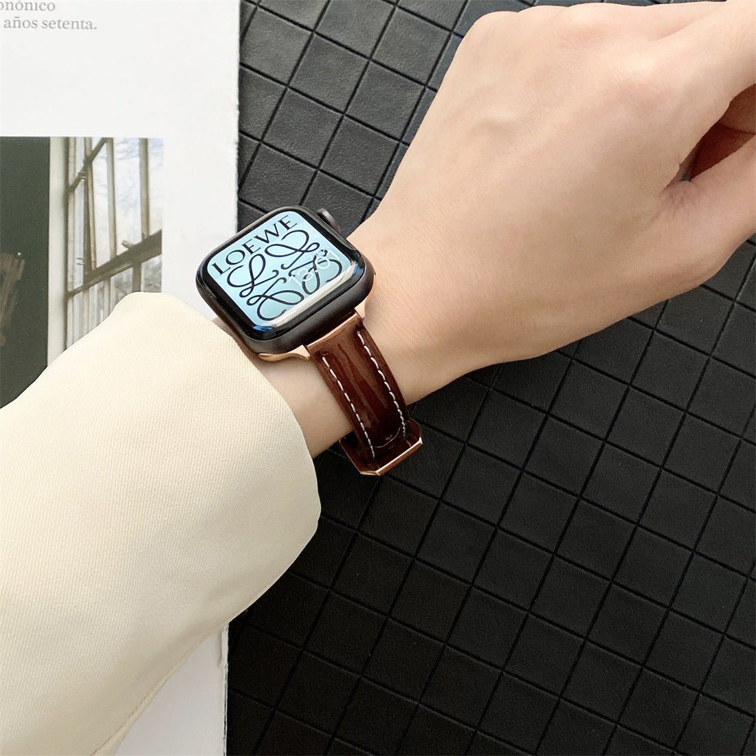 Bracelet Apple Watch en cuir marron foncé pour femme, élégant et ajusté, coutures apparentes blanches.
