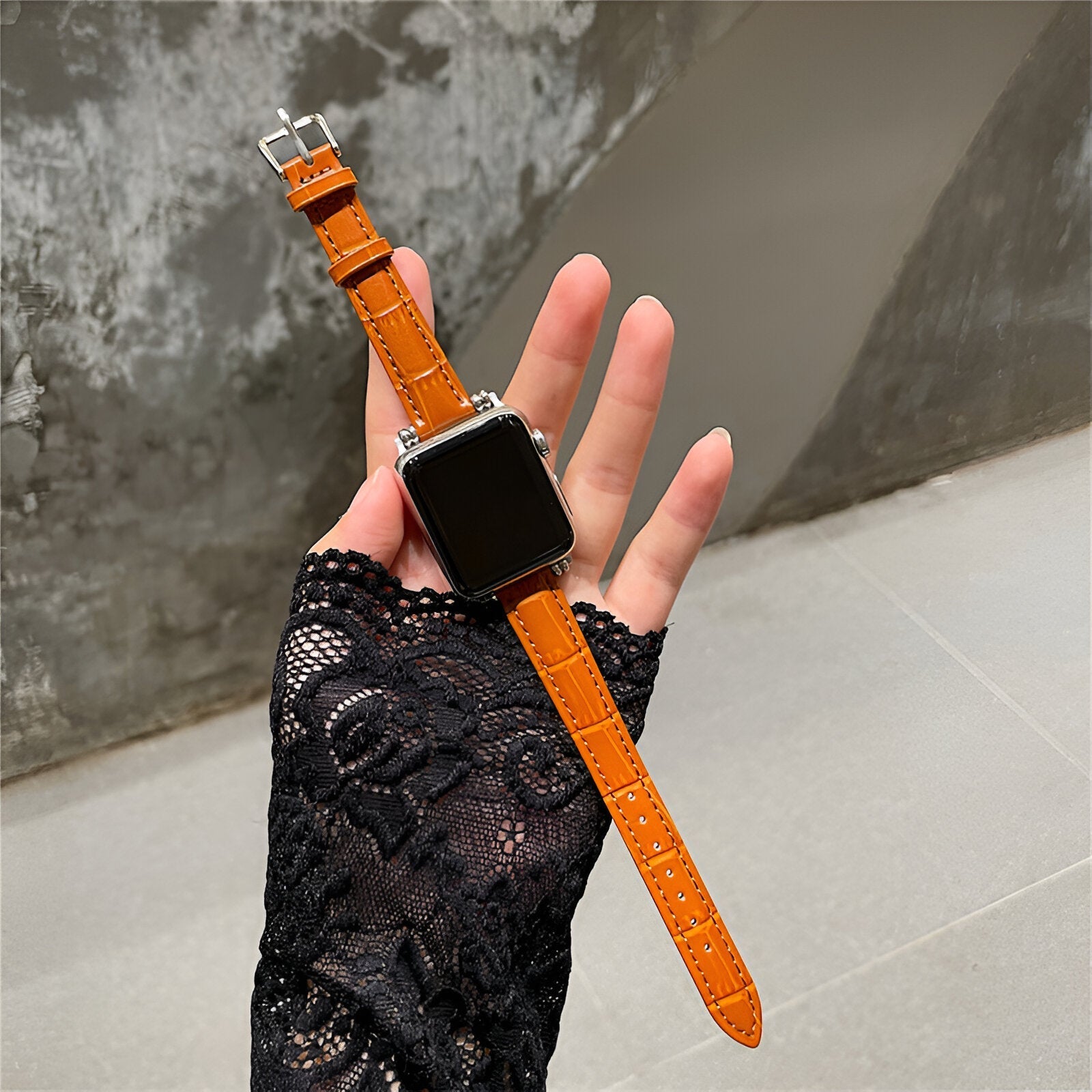 Bracelet microfibre orange pour Apple Watch avec boucle argentée, porté sur poignet en dentelle noire.