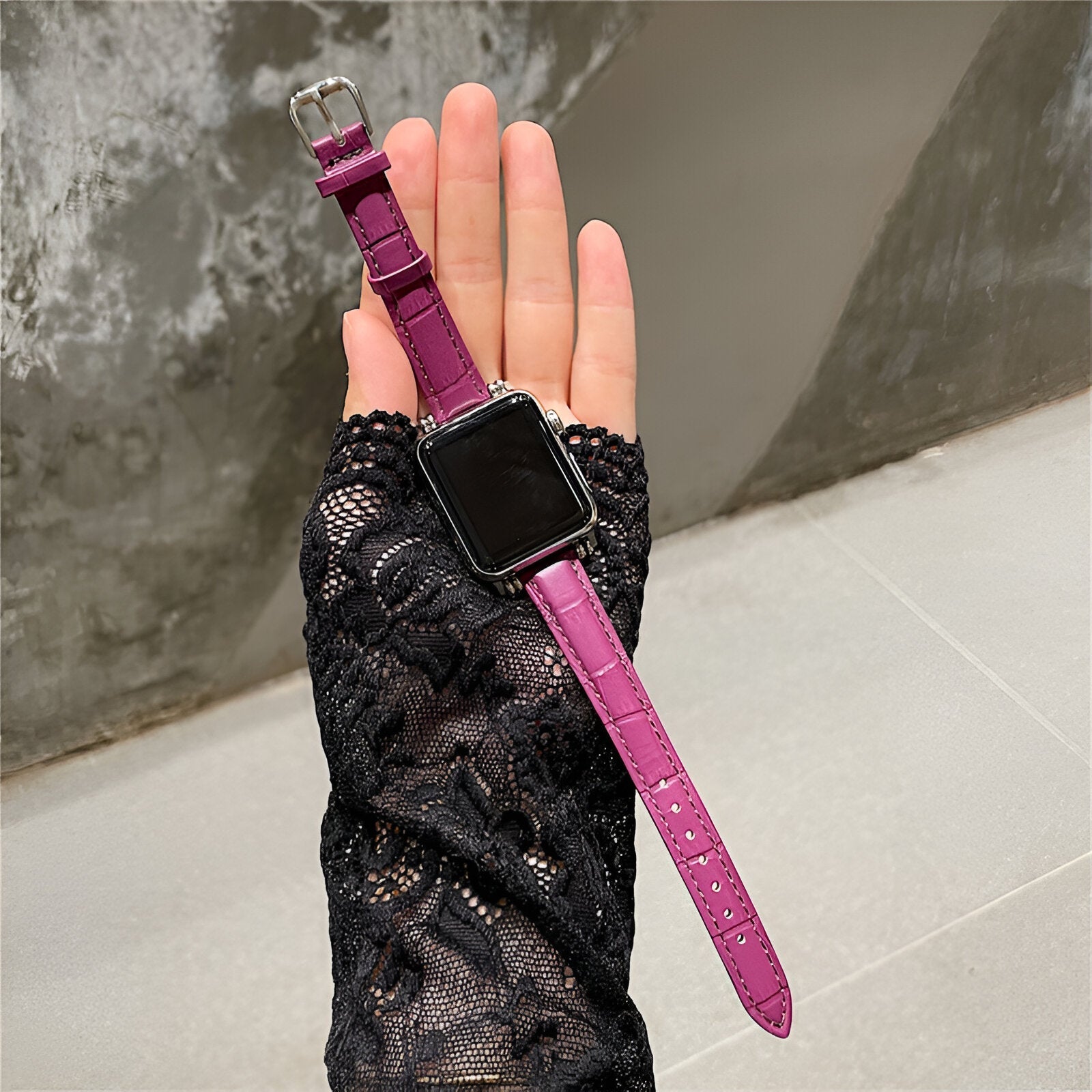 Bracelet Apple Watch en microfibre violet avec boucle argentée, porté sur main en dentelle noire.