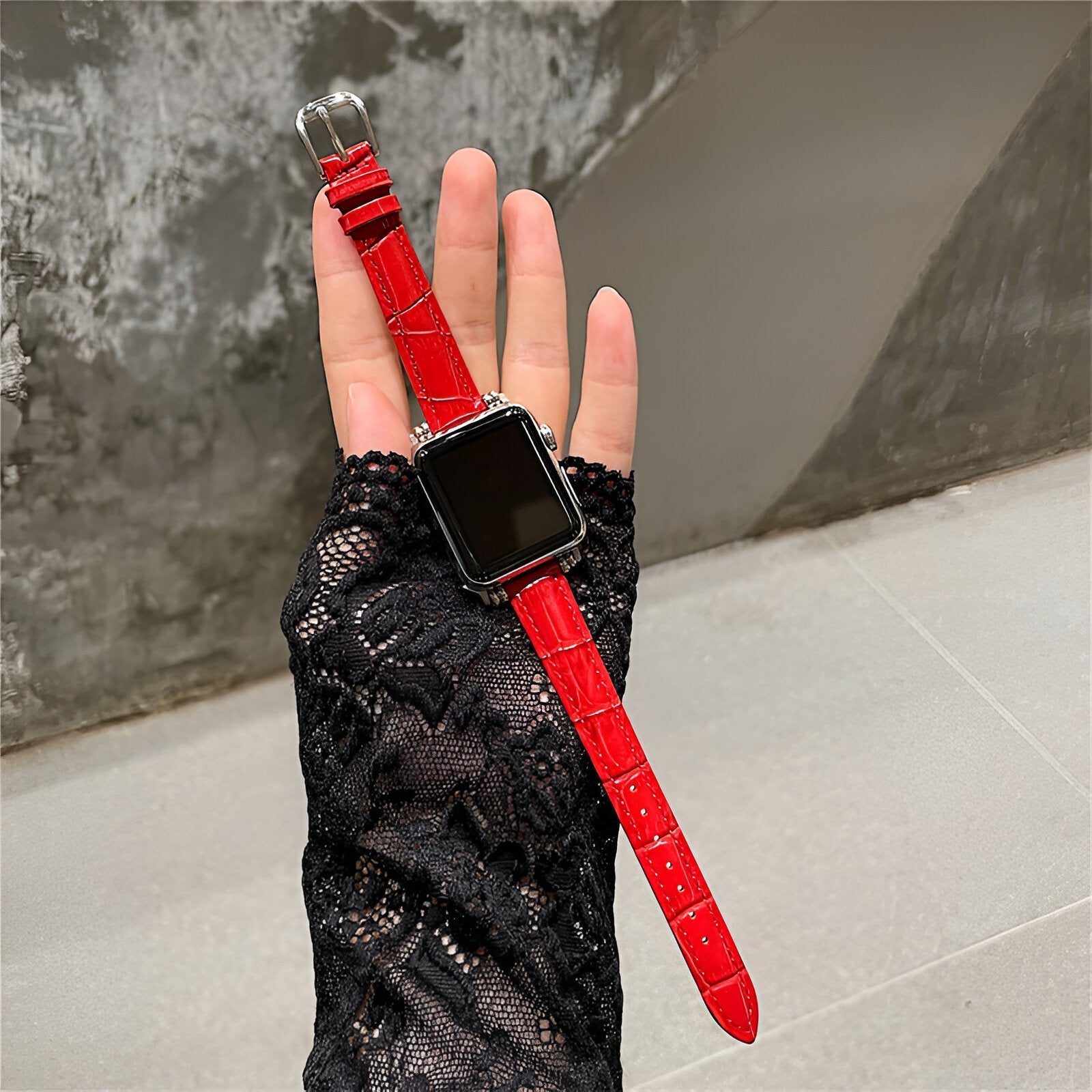 Bracelet Apple Watch en microfibre rouge brillant avec boucle argentée, porté sur main en gant noir dentelle.