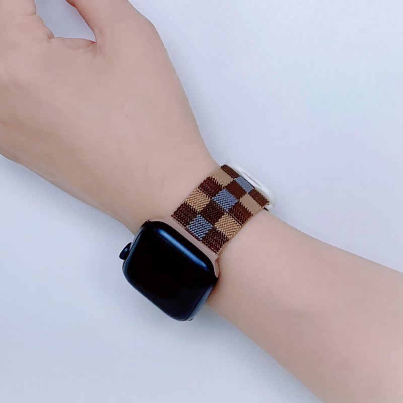 Bracelet Apple Watch en nylon à carreaux marron et beige, style mixte, porté au poignet.