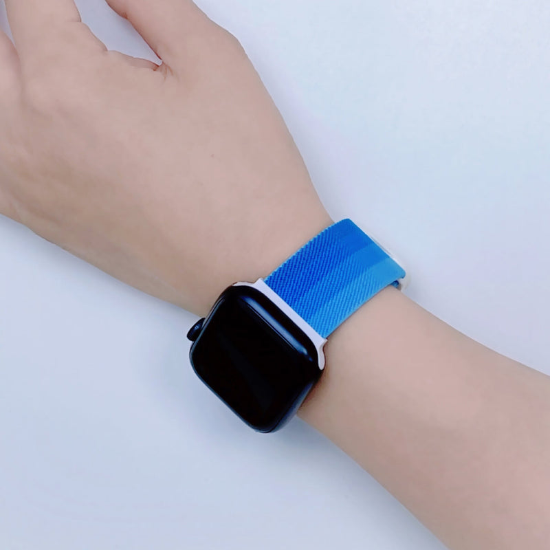 Bracelet Apple Watch en nylon dégradé bleu, ajustable, modèle Fenix, porté au poignet.