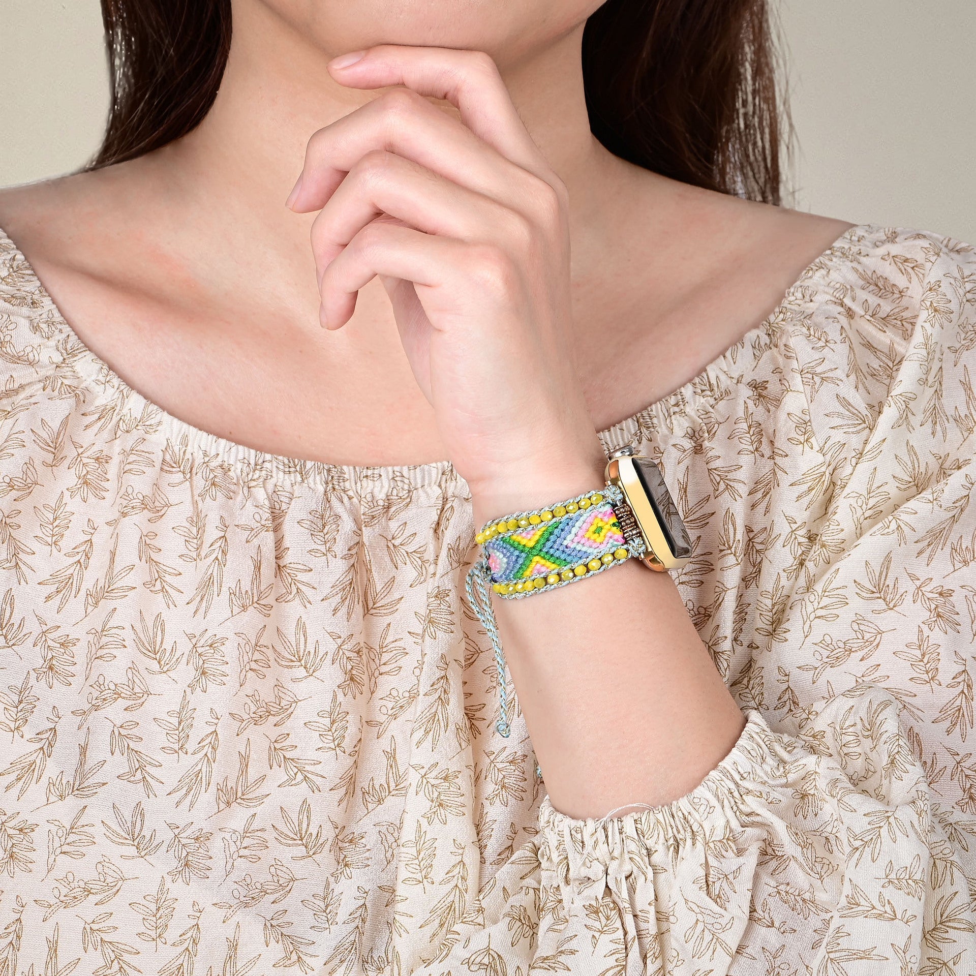 Bracelet Apple Watch Taelon en nylon vert avec motifs géométriques colorés et détails en cristal, porté au poignet féminin.
