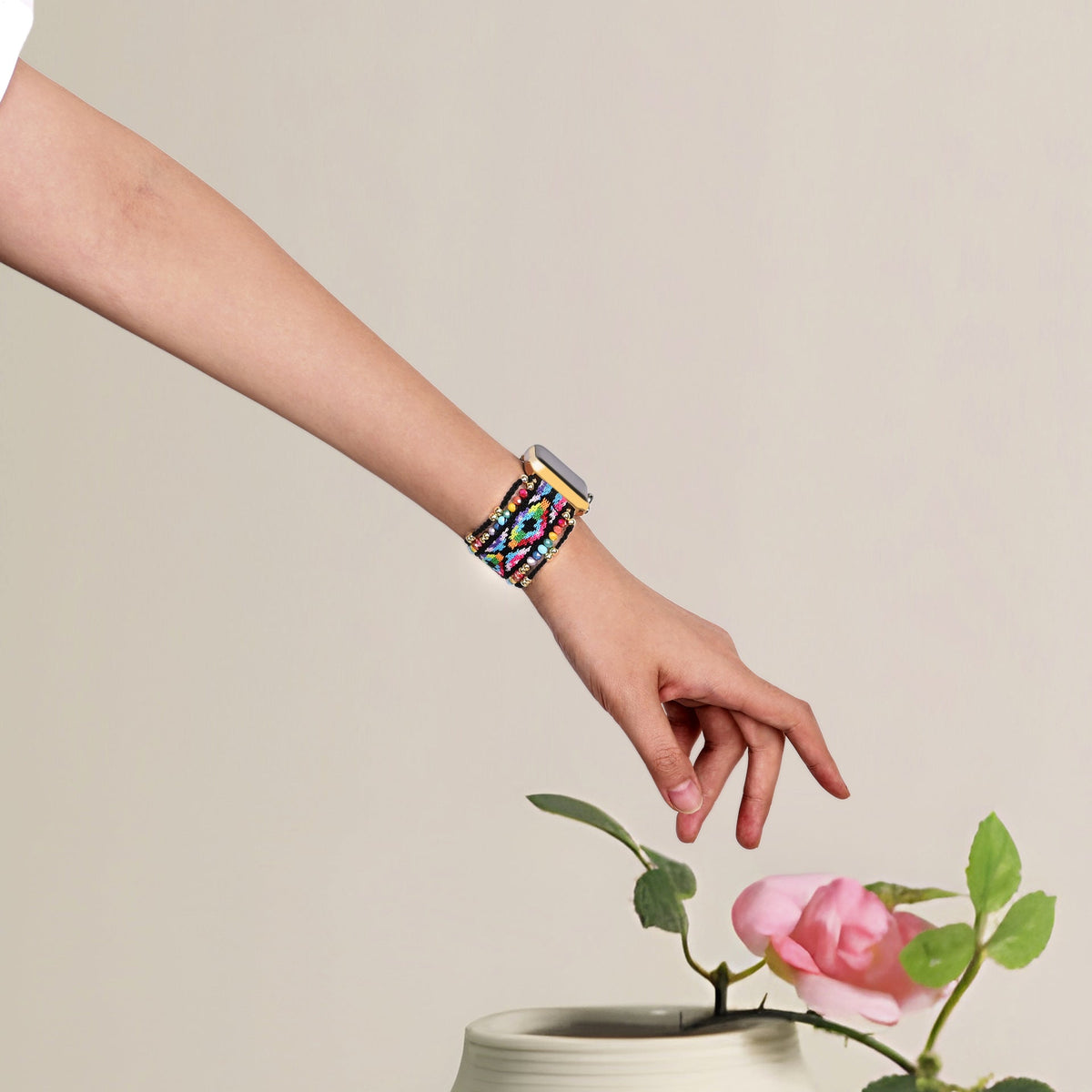 Bracelet Apple Watch multicolore en nylon tressé avec détails en cristal, porté au poignet femme.