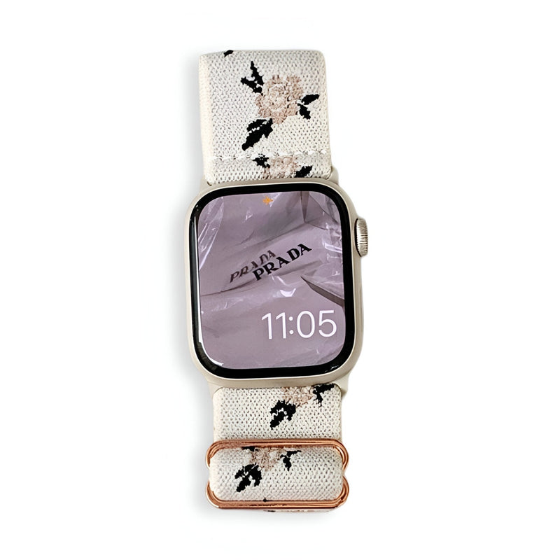 Bracelet Apple Watch en nylon blanc avec motifs floraux roses et verts, boucle cuivrée élégante.