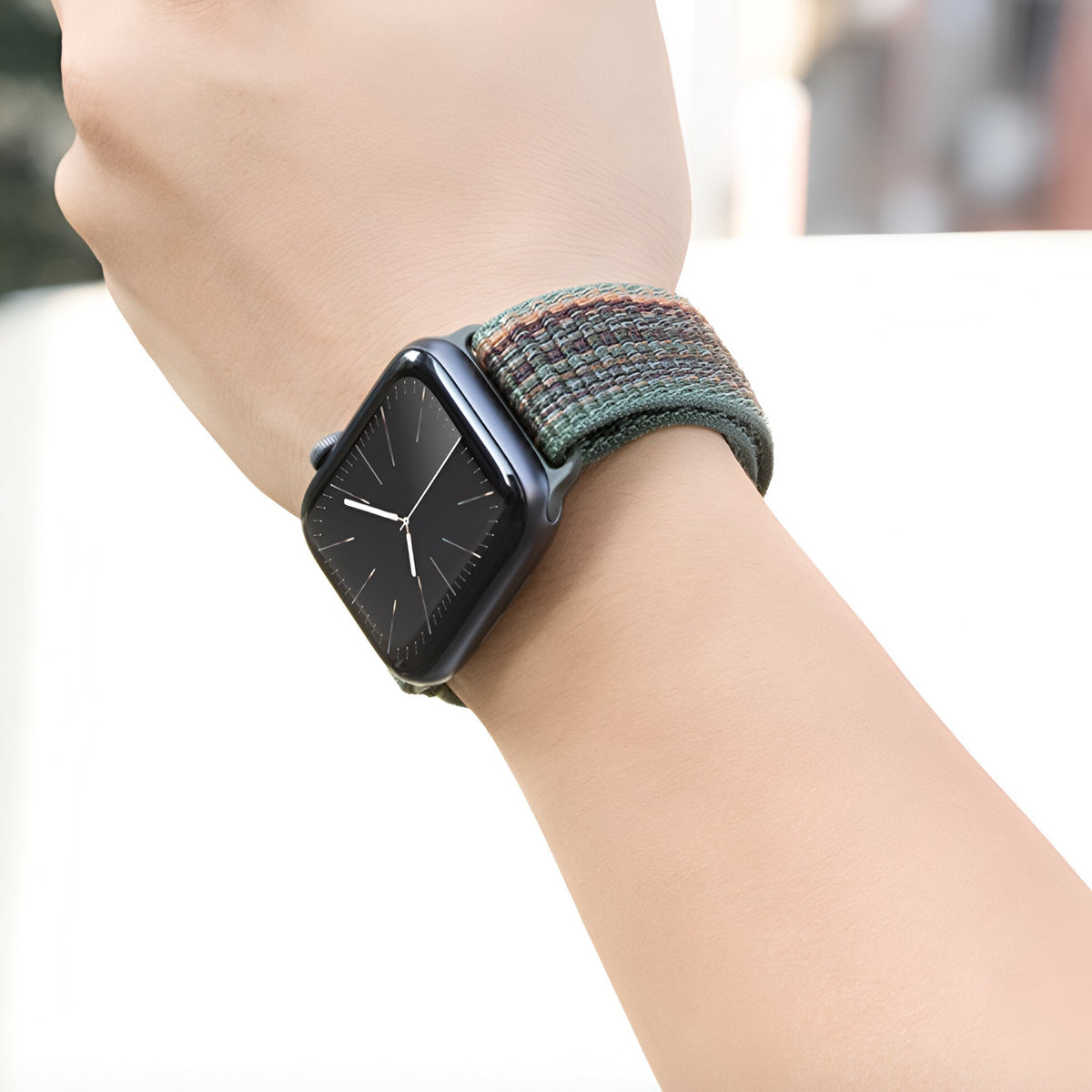 Bracelet Apple Watch en nylon tissé multicolore vert, orange et bleu, modèle Marix, porté au poignet.