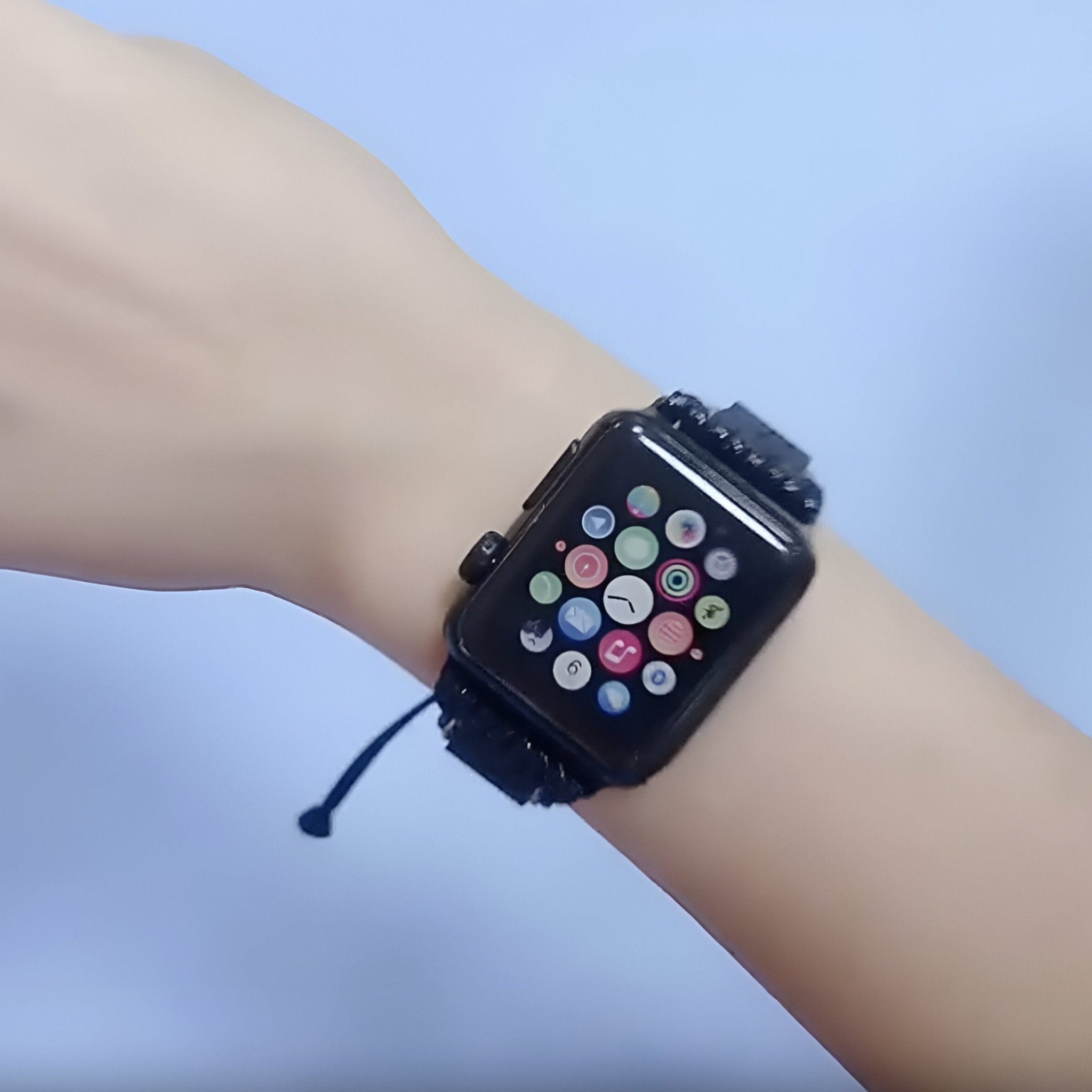 Bracelet Apple Watch noir en pierres volcaniques, style ajustable, porté au poignet féminin.