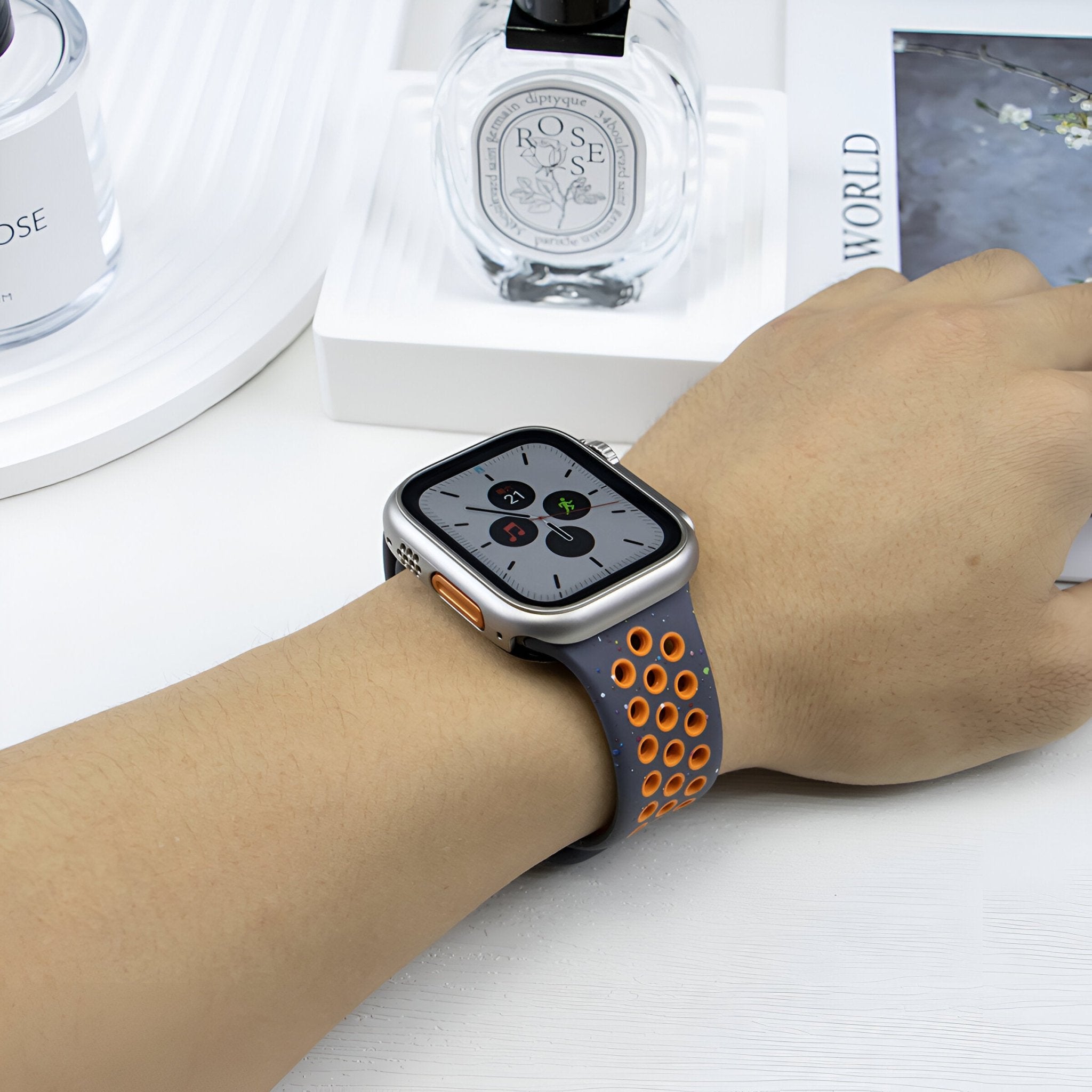 Bracelet Apple Watch Nyro en silicone noir avec perforations orange sur poignet féminin.