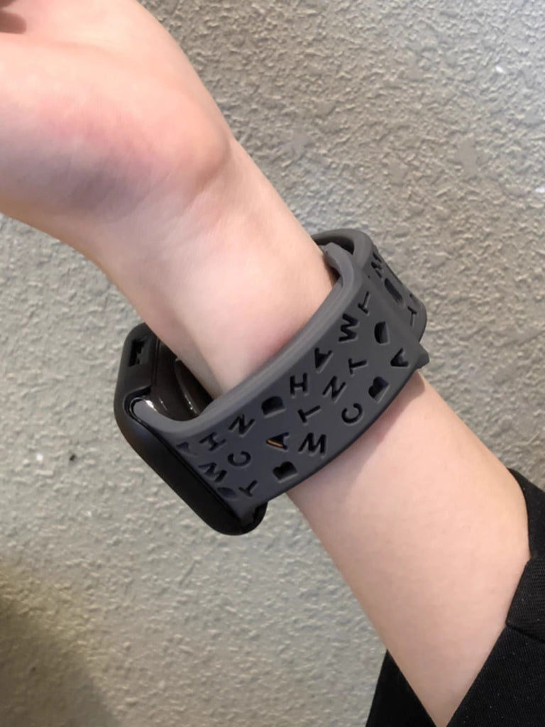 Bracelet Apple Watch silicone noir avec motifs lettres découpées, style ajustable femme.