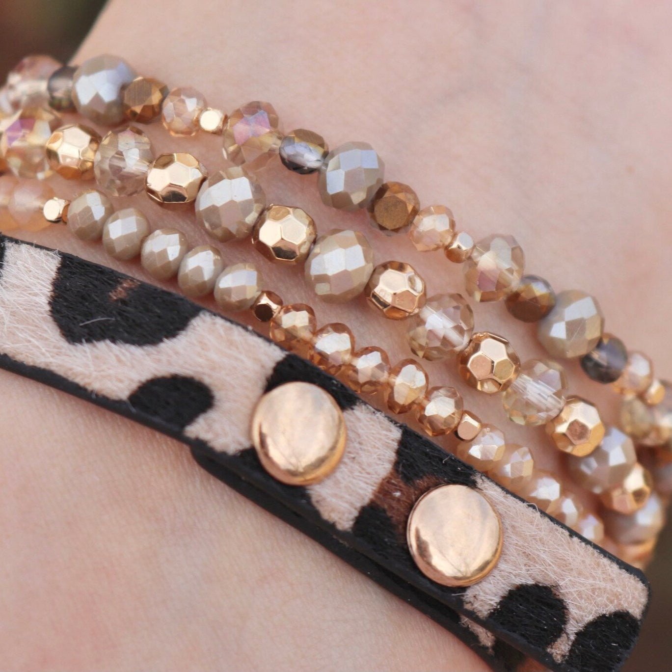 Bracelet Apple Watch multi-rangs perlé avec détails dorés et bande léopard en cuir doux.