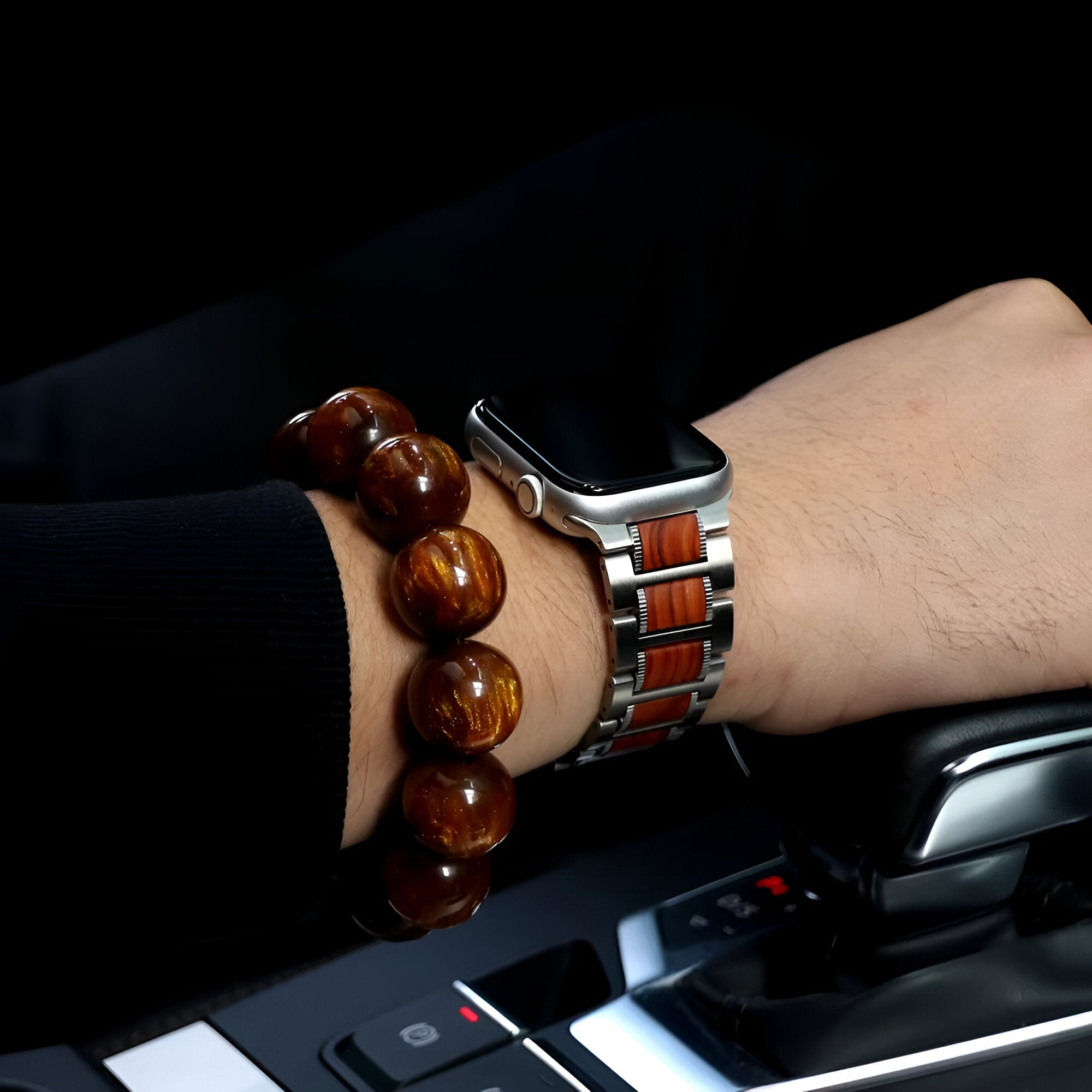 Bracelet de montre Apple Watch en bois de santal et métal argenté, porté au poignet d’homme avec bracelet en perles brunes.