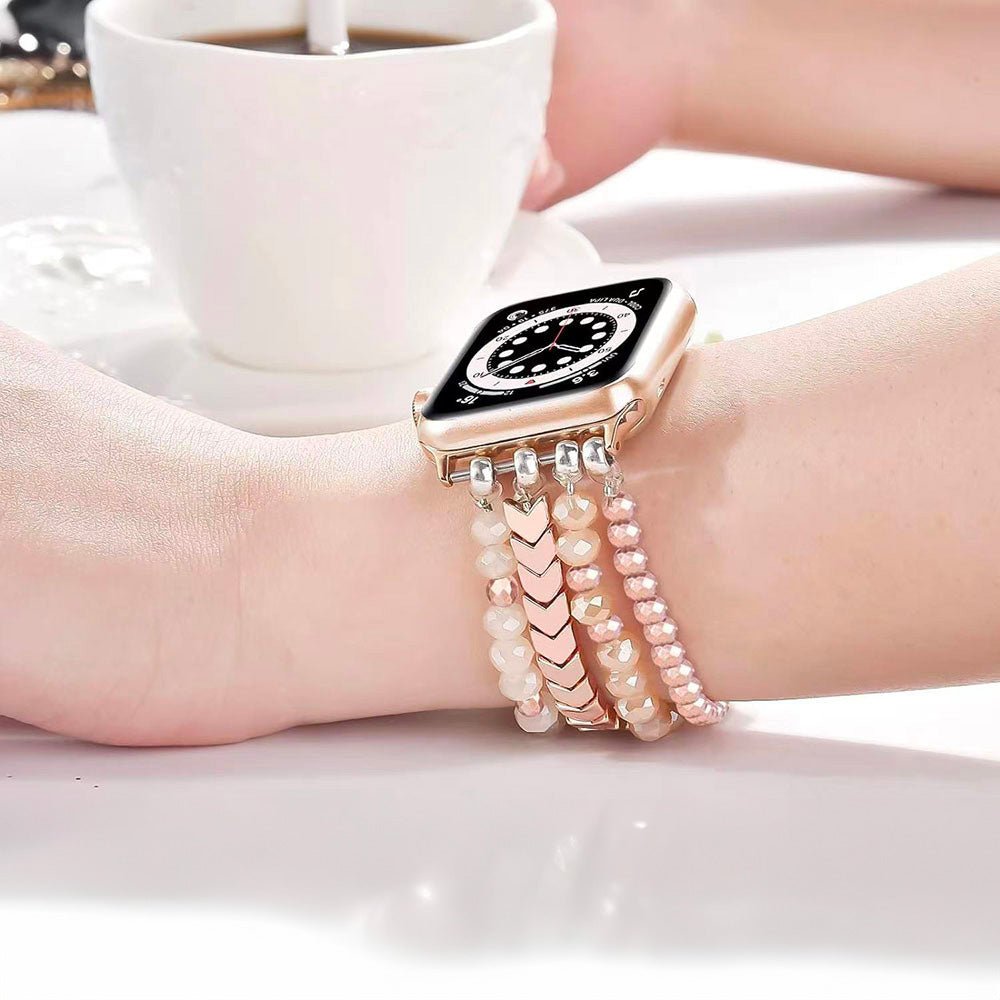 Bracelet de montre connectée rose en cristal scintillant orné de perles et maillons, style triple rangée.