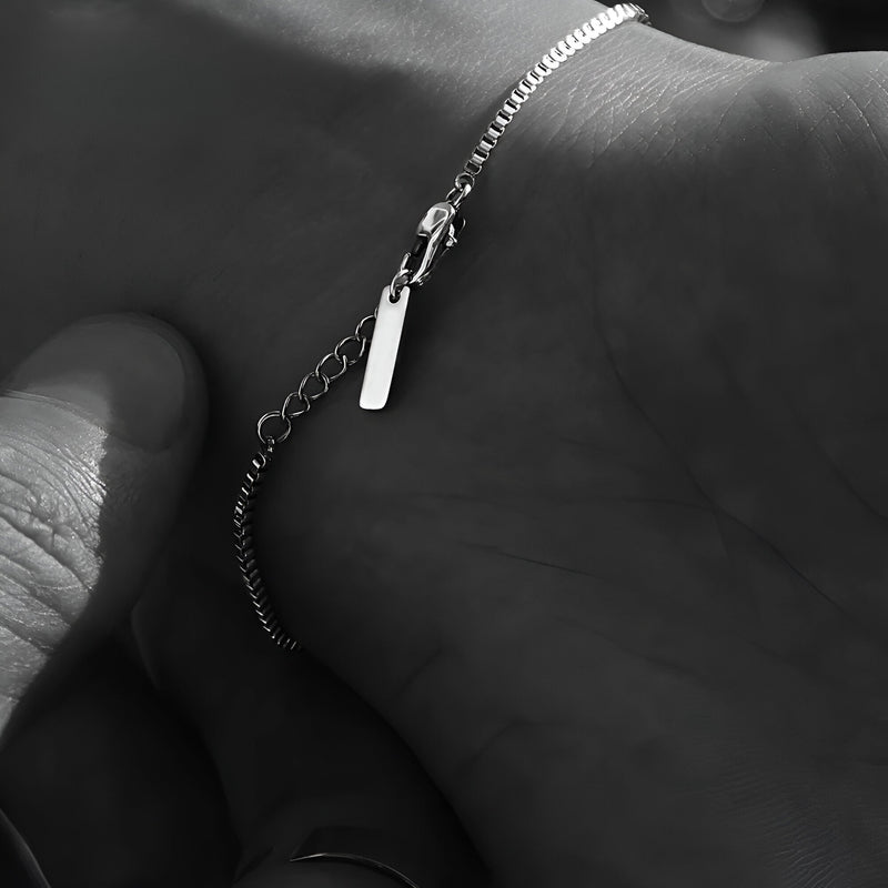Bracelet homme fin en acier inoxydable argenté avec petite plaque rectangulaire et chaîne délicate.