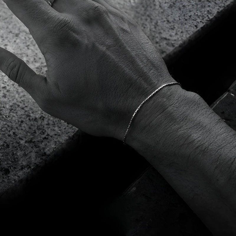 Bracelet fin en acier inoxydable argenté, design minimaliste, porté au poignet homme.