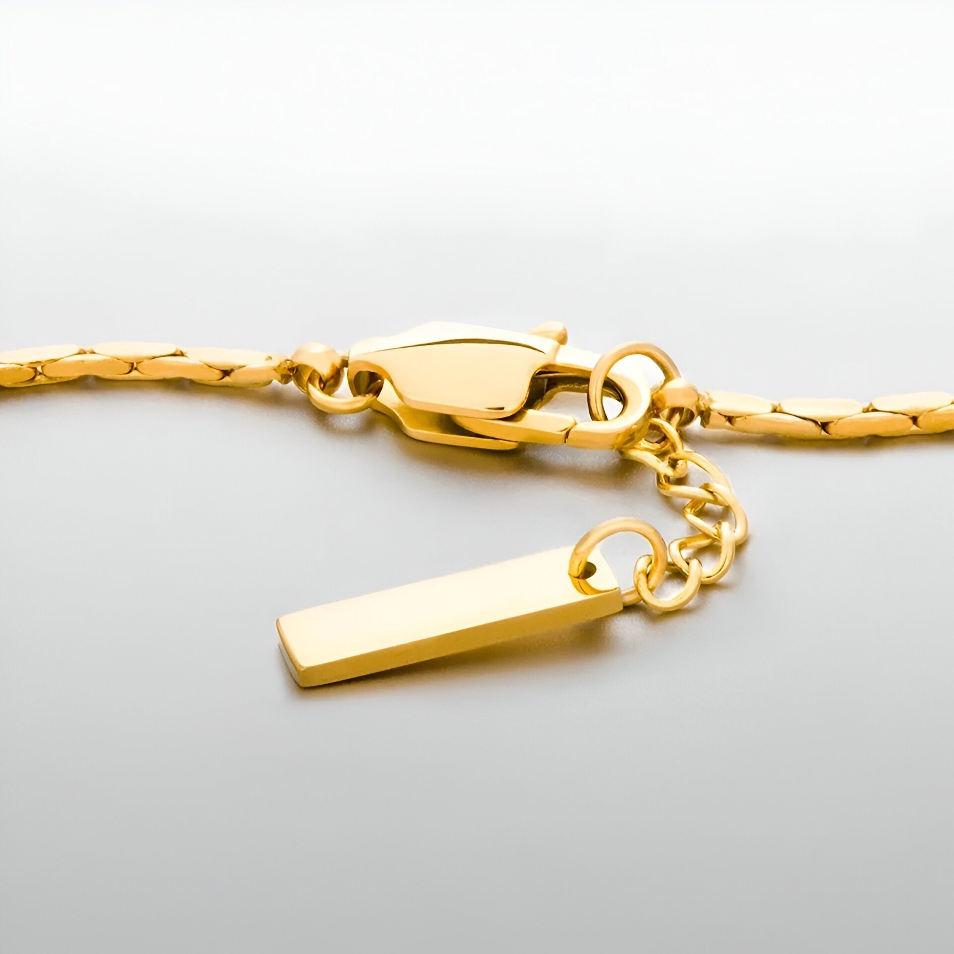 Bracelet homme fin en acier inoxydable doré avec fermoir mousqueton et chaîne d’extension.