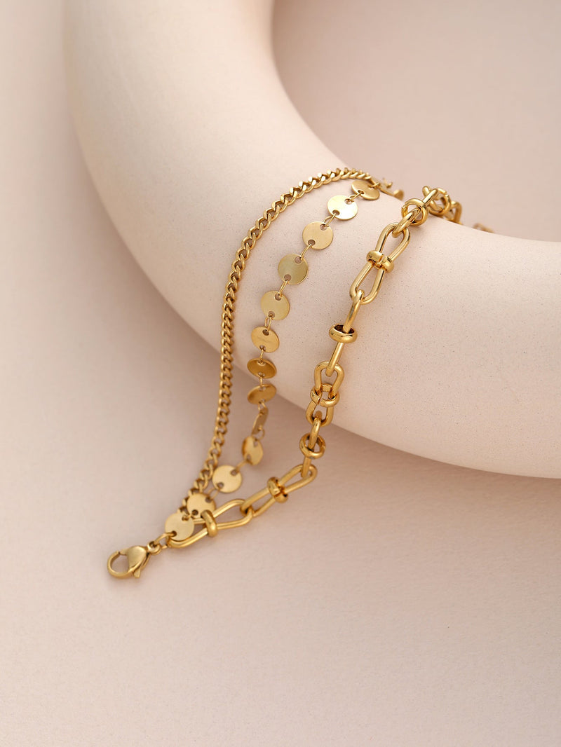Bracelet doré en acier inoxydable avec maillons variés et disques ronds brillants.