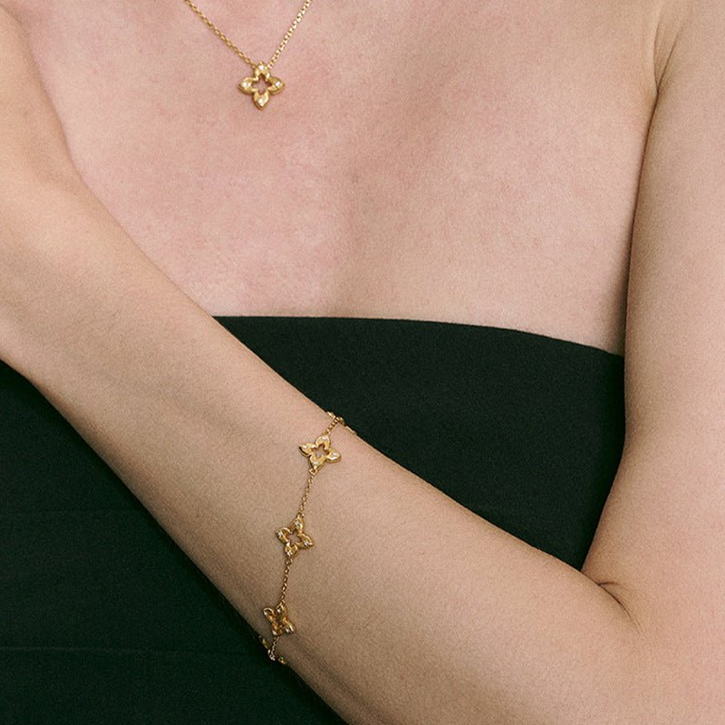 Bracelet doré en titane avec trois motifs trèfle ajourés et éclats de zircon sur chaîne fine plaquée or.