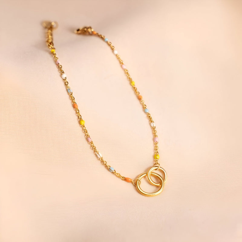 Bracelet doré pour femme avec deux anneaux entrelacés et chaîne délicate à maillons fins.